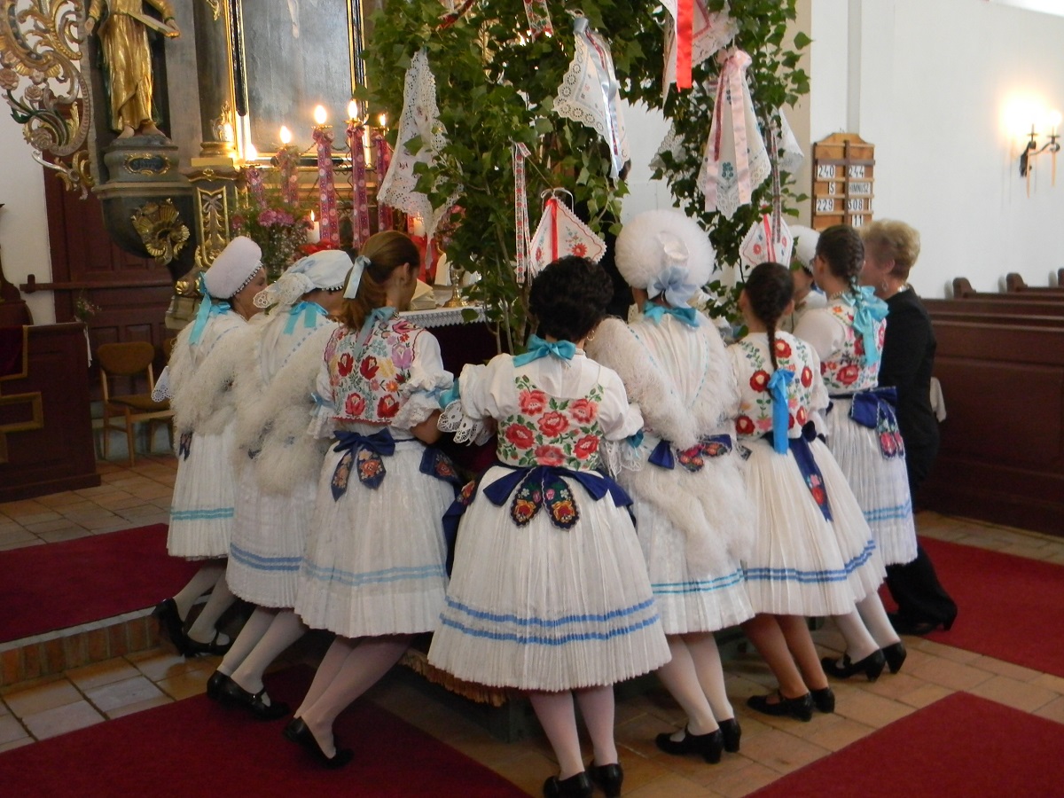 Lányok, asszonyok díszitik az evangélikus templom oltárát pünkösd szombatján